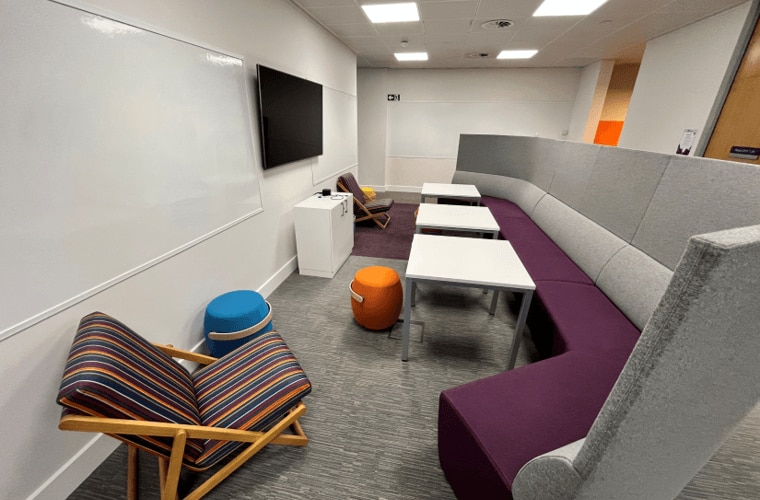 A seating area with a large sofa and a TV screen on the wall.