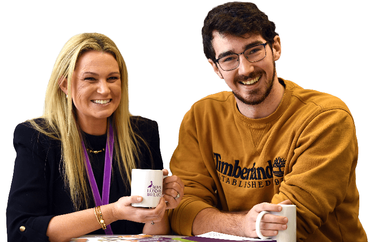 Two colleagues with hot drinks talking and smiling.