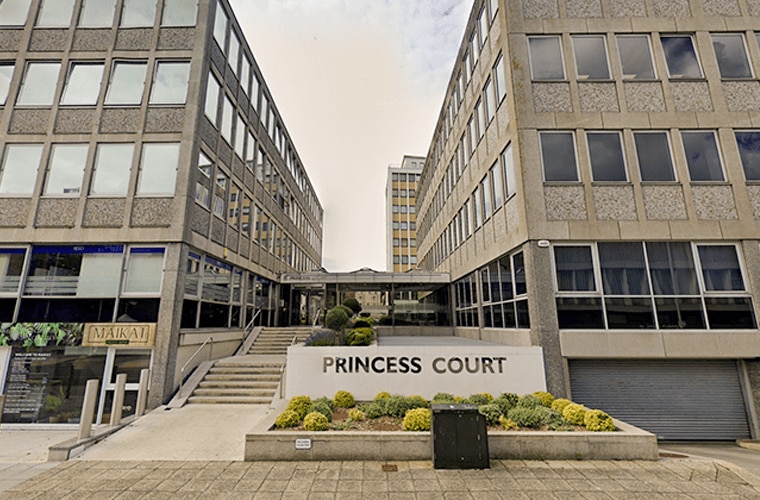 A building separated by steps and green bushes.
