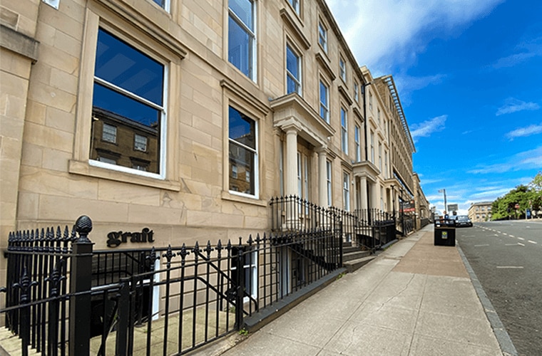 A Victoria stone building with columns, steps and black iron railings.