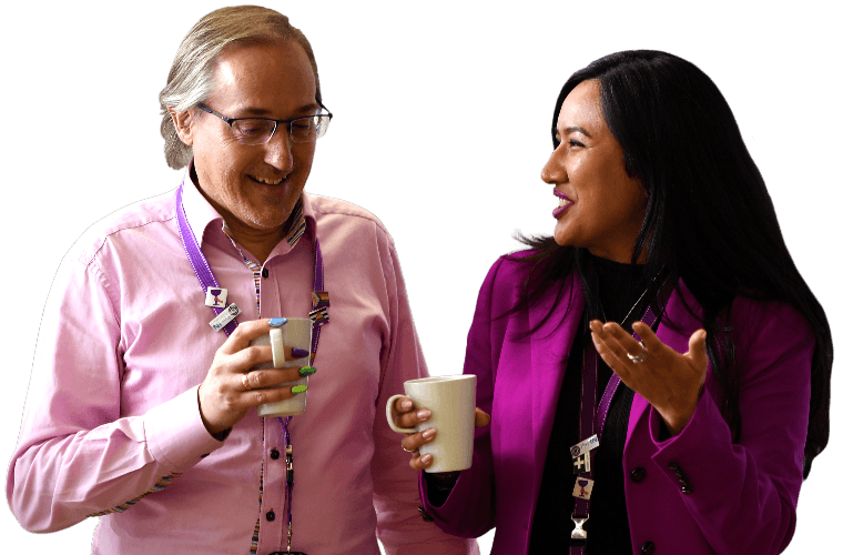 Two colleagues talking and walking with hot drinks.