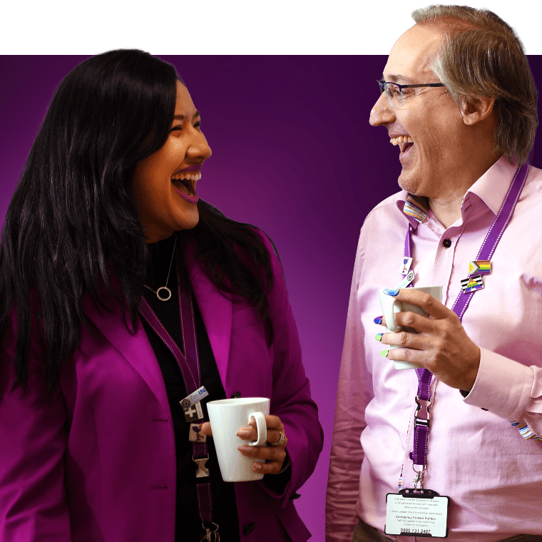 Two colleagues talking and laughing over a hot drink.