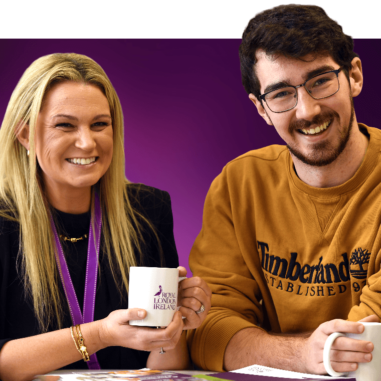 Two colleagues with hot drinks talking and smiling.