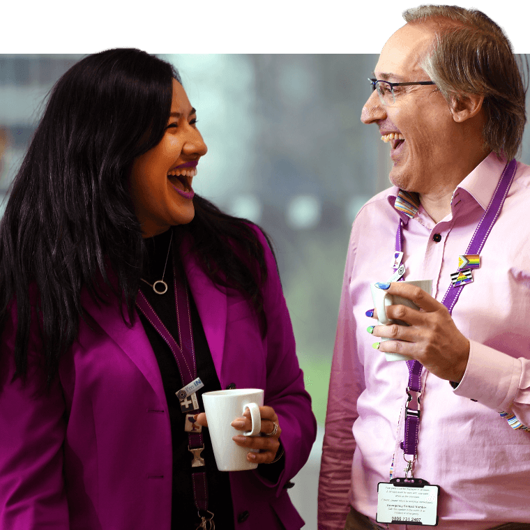 Two colleagues talking and laughing over a hot drink.
