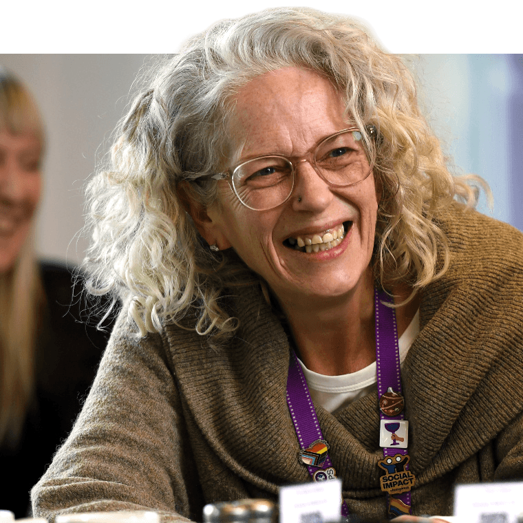 A colleague smiling over a table with hot drinks.