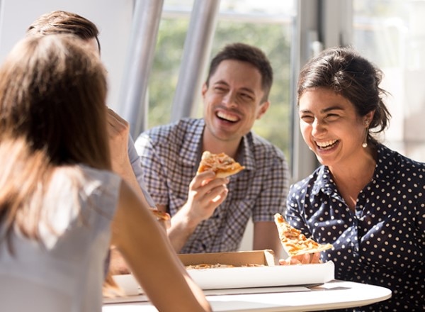 Colleagues enjoying each other’s company and pizza for lunch. 