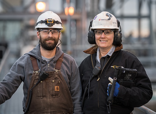 One man and one woman wearing Xcel Energy safety gear smile