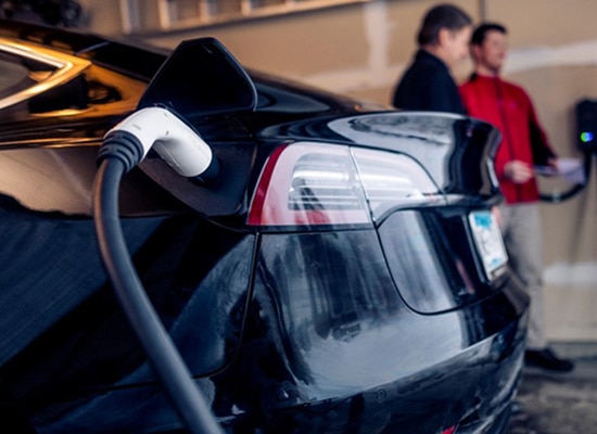 Closeup view of black electric car being charged