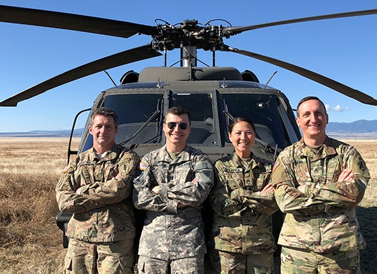 Military personnel standing in front of a helicopter