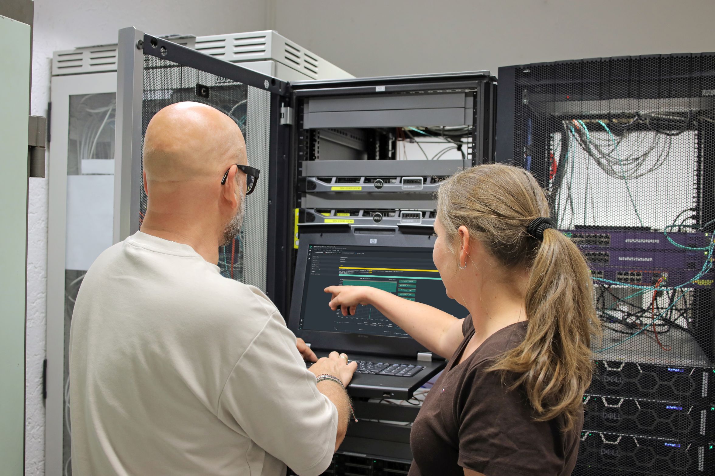 Eine Kollegin zeigt ihrem Kollegen etwas auf einem Bildschirm im Server-Raum