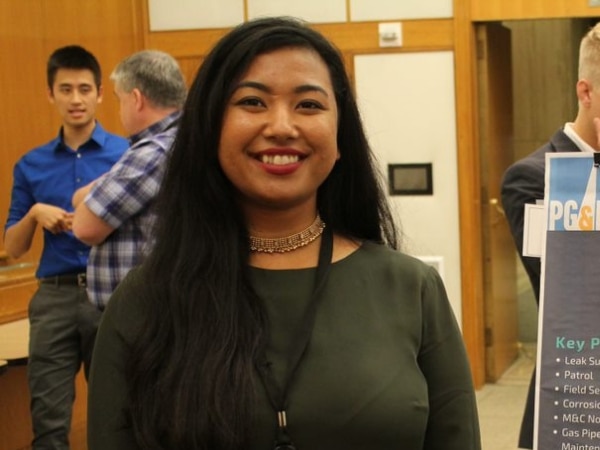 Intern stands next to her summer poster project and smiles at the camera