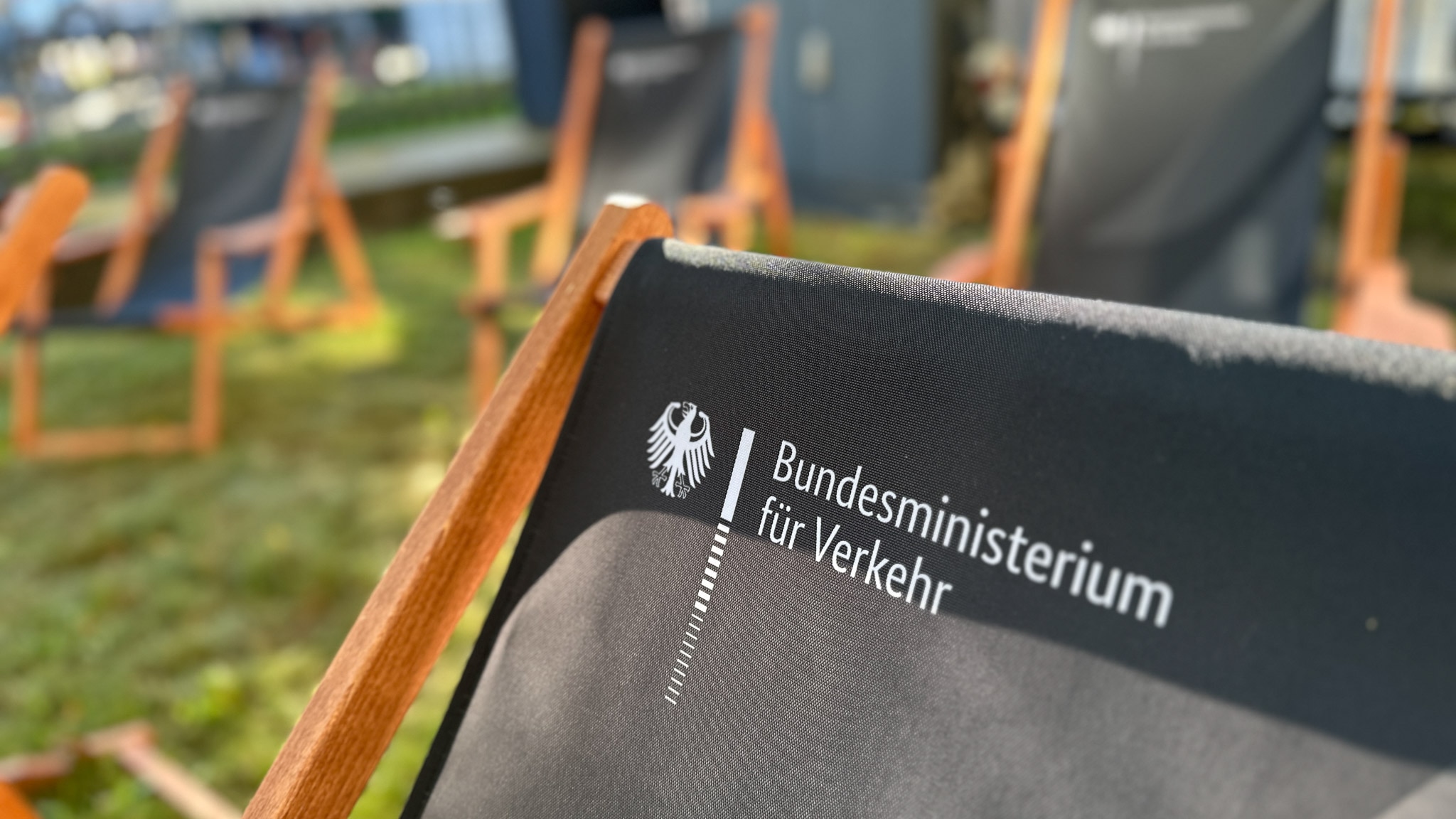 Liegestühle mit Aufschrift „Bundesministerium für Verkehr“ auf einer Wiese.