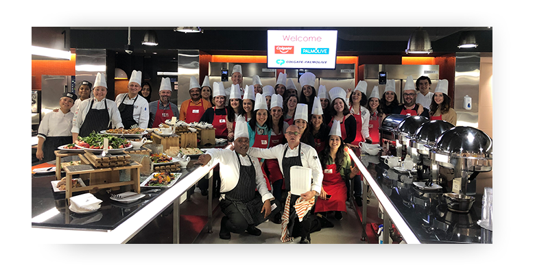 Group of employees wearing chefs hats in a commercial kitchen for a cooking class