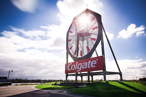 Grande relógio da Colgate ao centro da imagiem com um céu azul ao fundo.