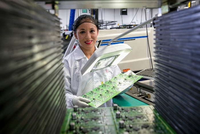 Female Celesctica employee inspecting a circuit board.