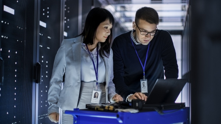 Doi angajați care lucrează împreună pe un computer