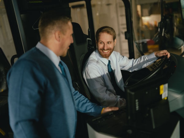 Zwei Männer in Uniform lachend im PostAuto