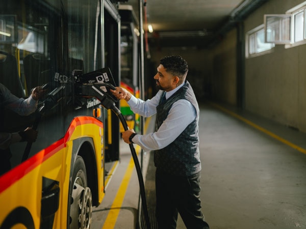 Mann in Uniform tankt ein PostAuto