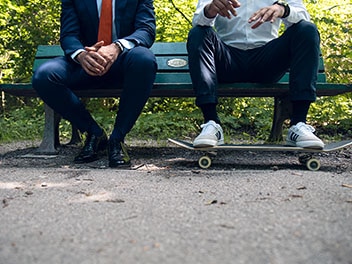 Due impiegati di Allianz seduti su una panchina del parco in stile business e casual senza testa.
