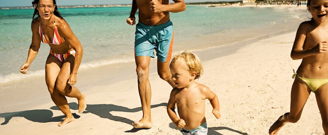 Family runs on the sand on a beach