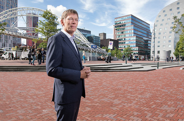 We zien hier collega Paul de Vries in pak(maatwerk & advies) op een plein in Rotterdam