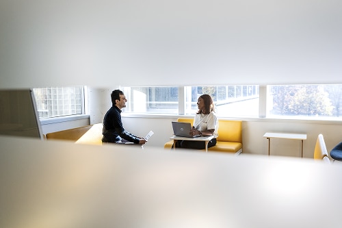 An image of two people having a conversation in a lounge.