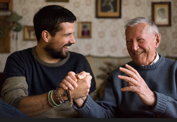 An older and younger man smiling and clasping hands showing camaraderie