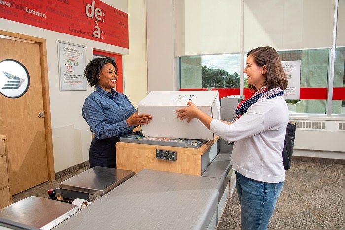 A Canada Post Woman Postal worker Ppacing a parcel to a customer in a Post Office 