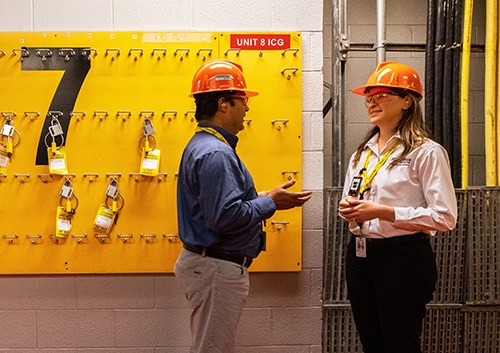 A female supervisor speaks consults another employee in a hallway.